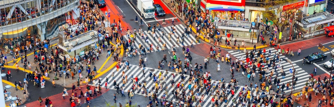 crowd of people crossing busy street demonstrating need for awareness of surroundings